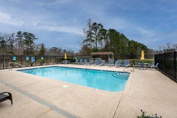 a swimming pool with lounge chairs and umbrellas